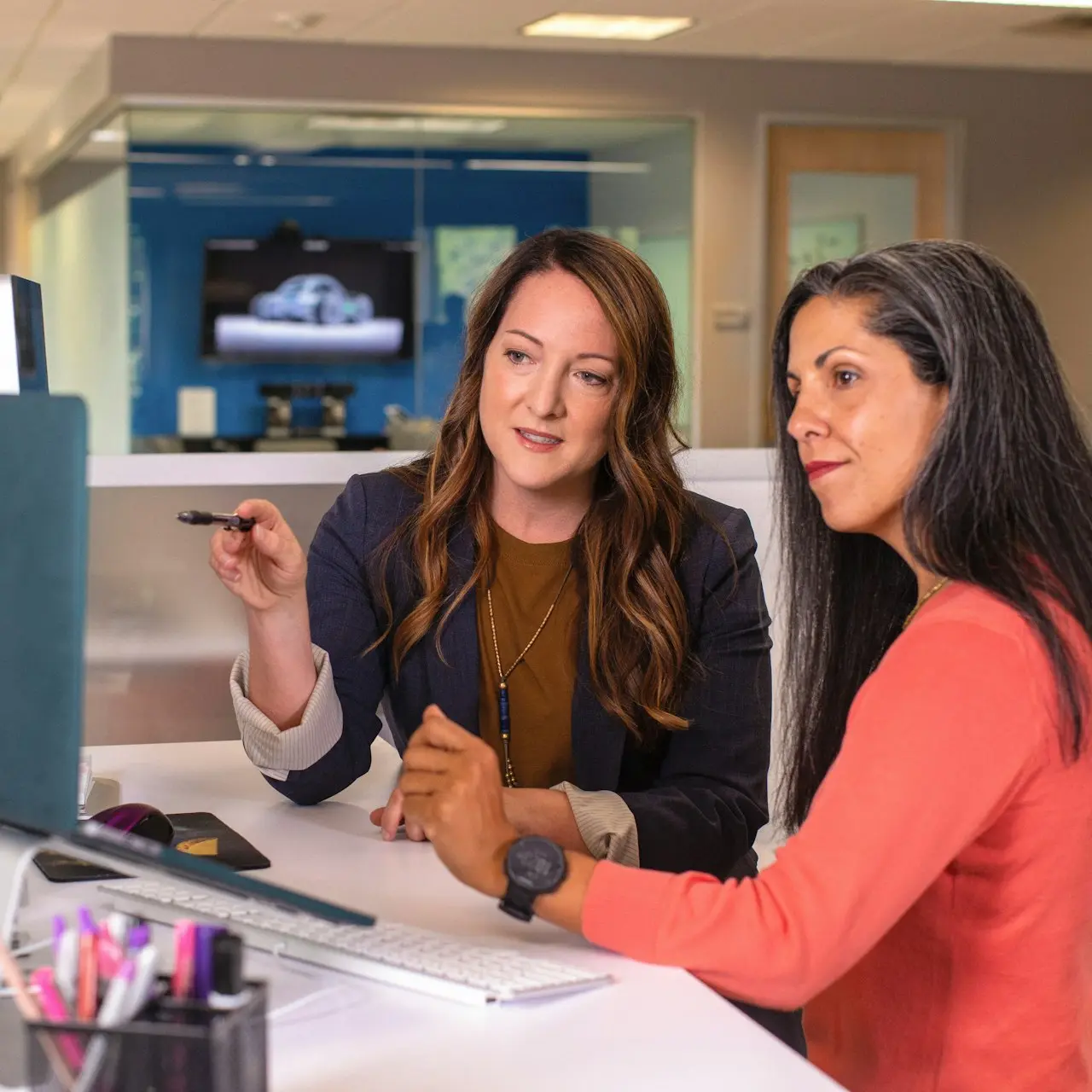 two women sitting at a table looking at a computer screen
