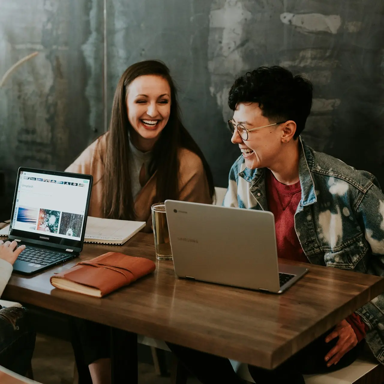 three people sitting in front of table laughing together