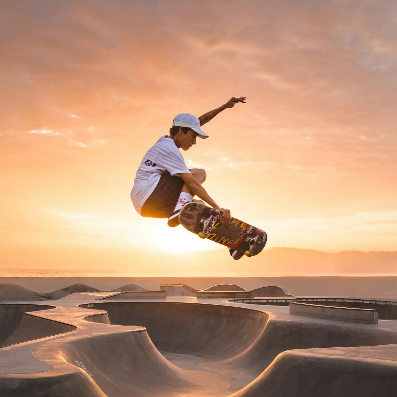 man in white t-shirt and brown pants riding skateboard on brown sand during daytime