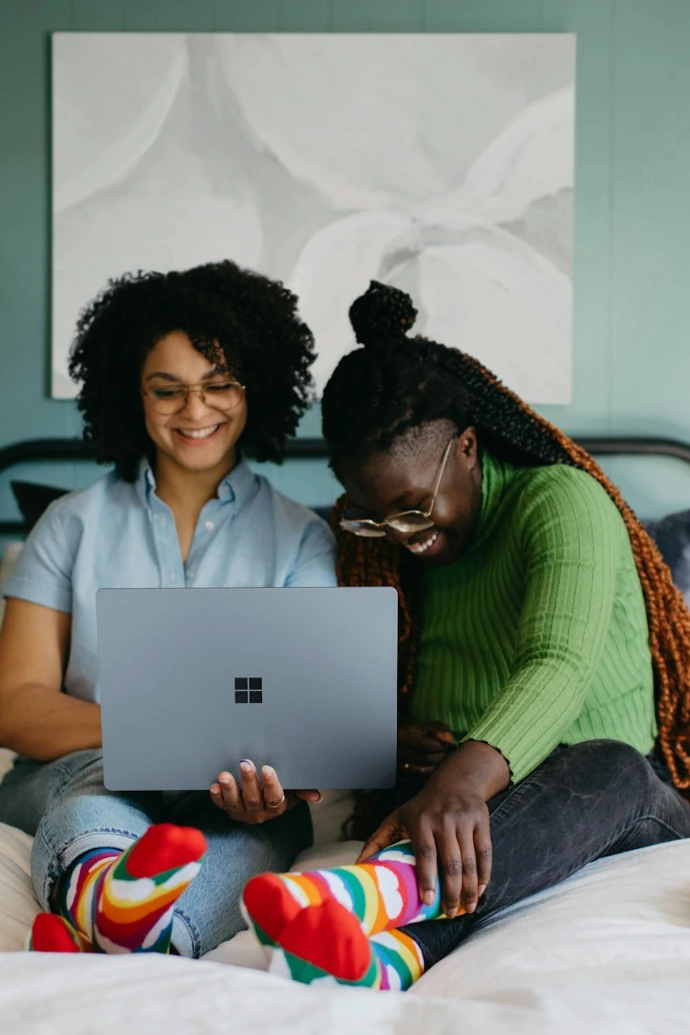 a woman sitting on a bed using a laptop
