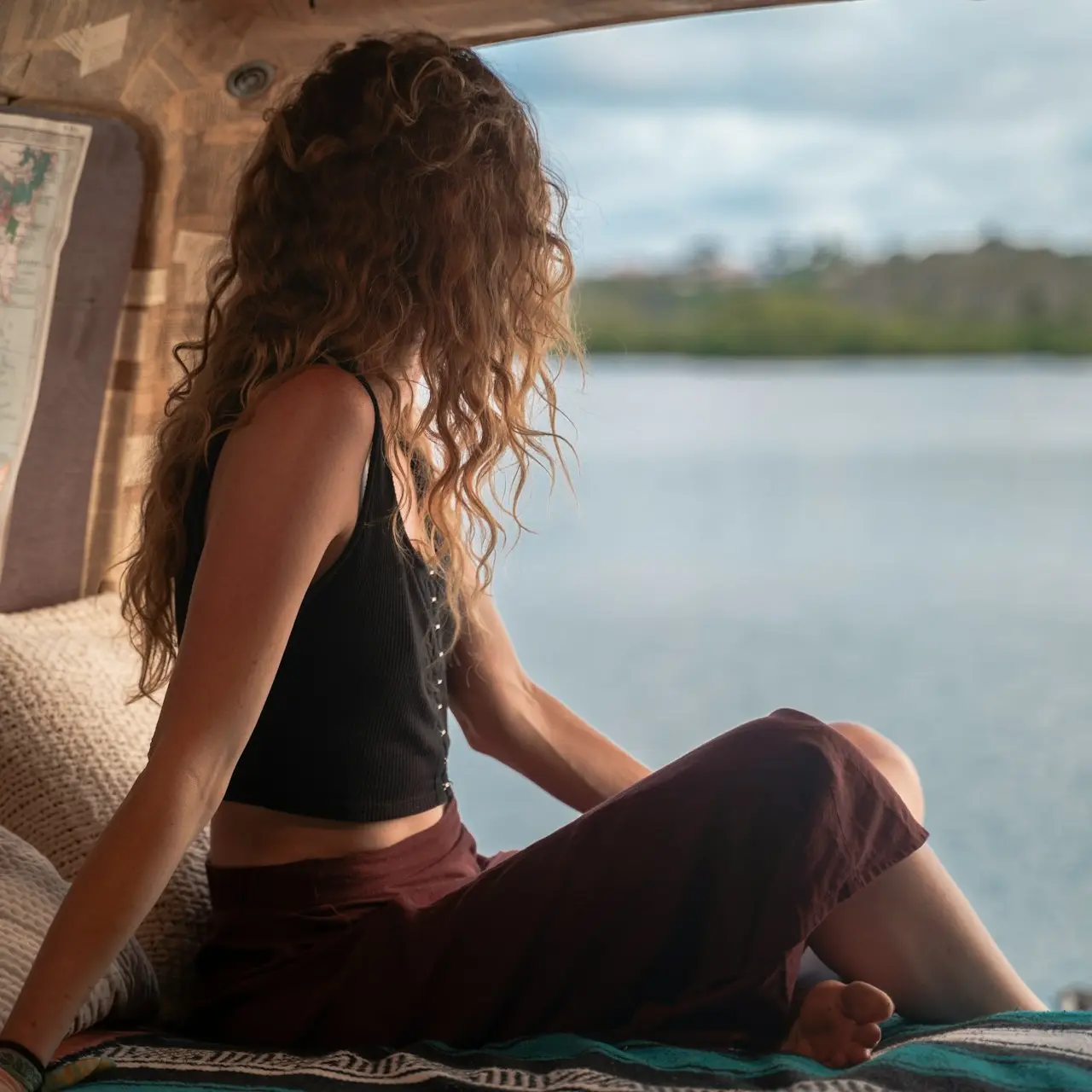 woman wearing black spaghetti strap top sitting viewing body of water