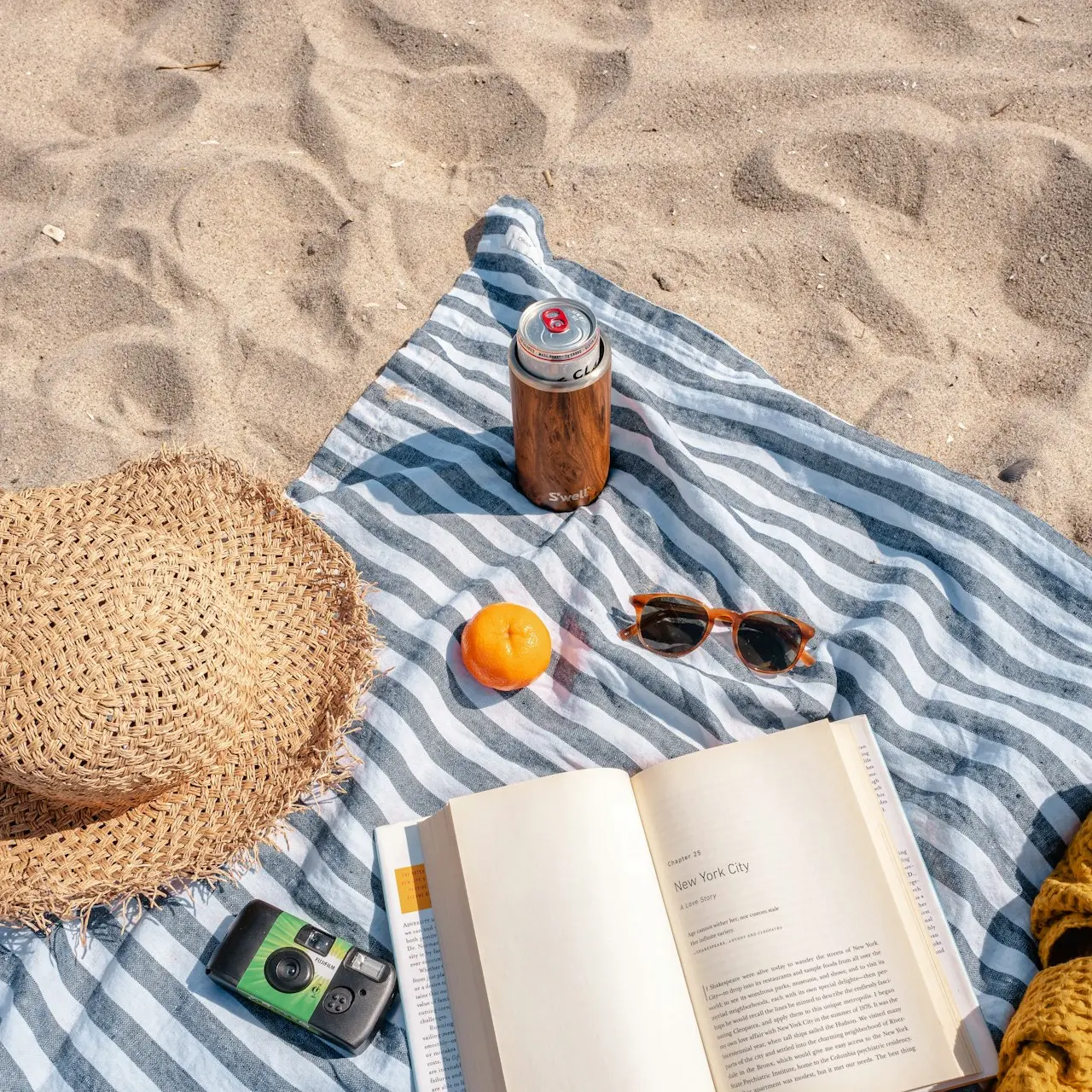 brown glass bottle beside white book on blue and white textile